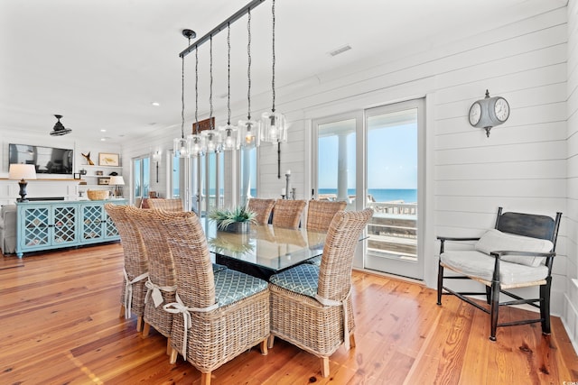 dining area featuring light wood-type flooring and a water view