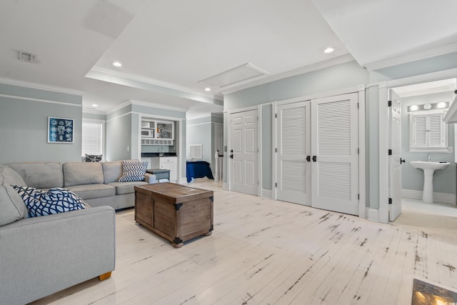 living room featuring ornamental molding, sink, and light hardwood / wood-style floors