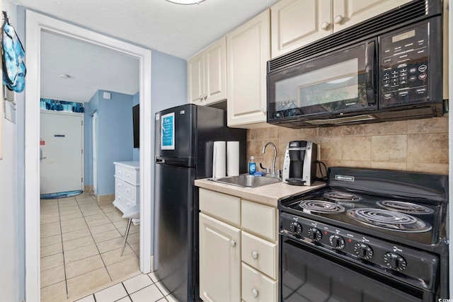 kitchen featuring sink, decorative backsplash, light tile patterned floors, black appliances, and a textured ceiling