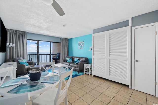 tiled dining area featuring a water view, ceiling fan, and a textured ceiling