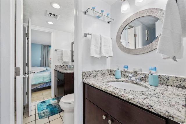 bathroom with vanity, a textured ceiling, tile patterned floors, and toilet