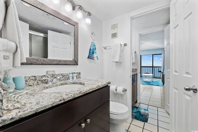 bathroom featuring a shower with door, tile patterned flooring, vanity, a textured ceiling, and toilet