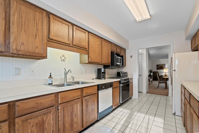 kitchen featuring tasteful backsplash, sink, light tile patterned floors, and white appliances