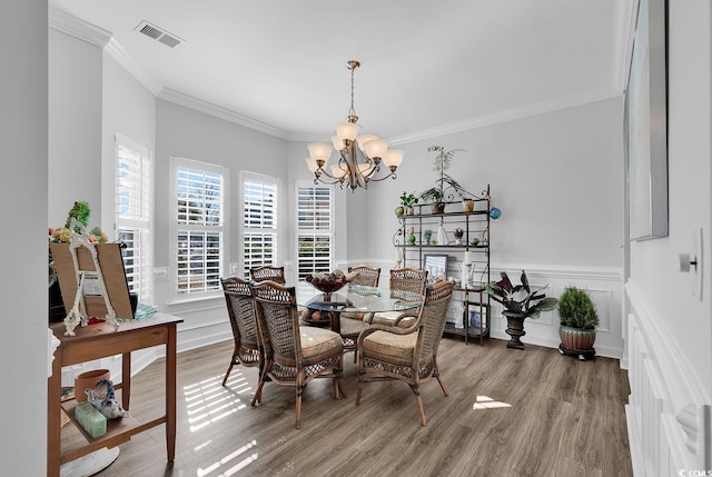 dining space featuring hardwood / wood-style floors, crown molding, and a chandelier