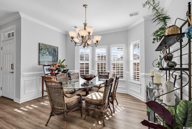 dining area featuring ornamental molding, hardwood / wood-style floors, and a chandelier