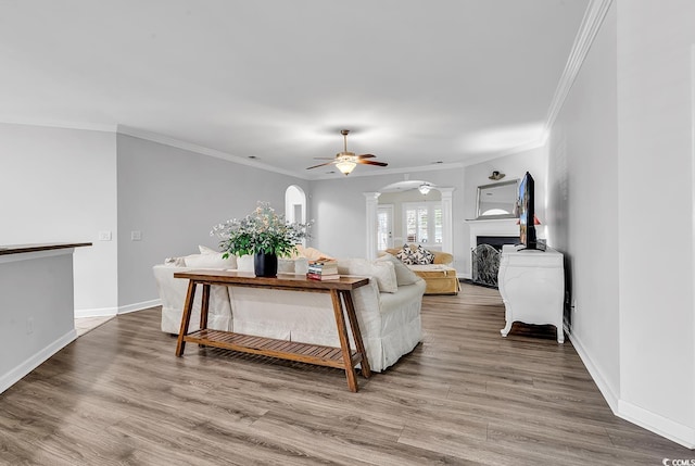 living room with crown molding, wood-type flooring, and ceiling fan