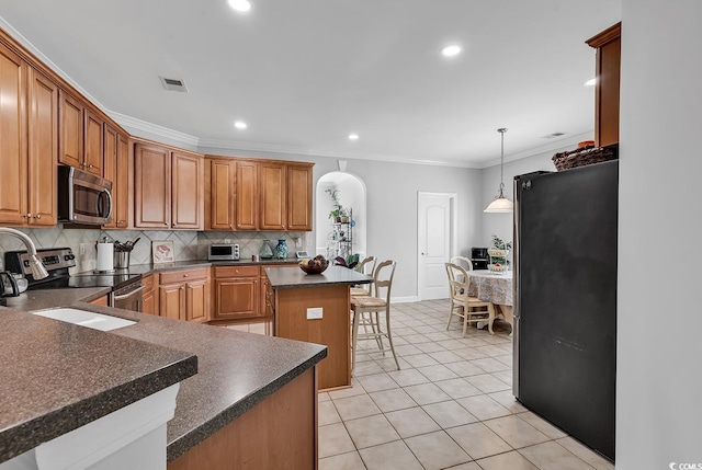 kitchen with pendant lighting, a breakfast bar, stainless steel appliances, a center island, and decorative backsplash