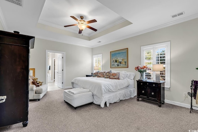 carpeted bedroom featuring crown molding, ceiling fan, a tray ceiling, and ensuite bath