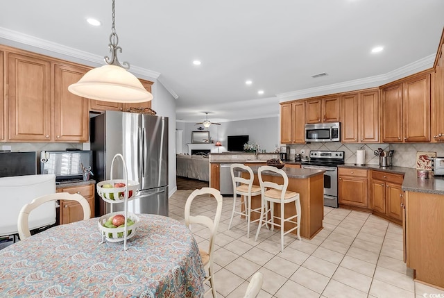 kitchen with stainless steel appliances, ornamental molding, light tile patterned floors, and decorative light fixtures