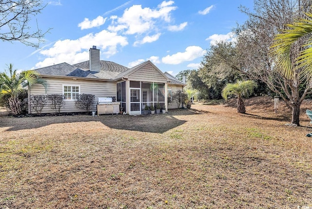 back of house featuring a sunroom and a lawn