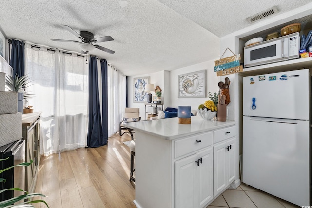 kitchen featuring white cabinetry, white appliances, ceiling fan, a textured ceiling, and light hardwood / wood-style flooring