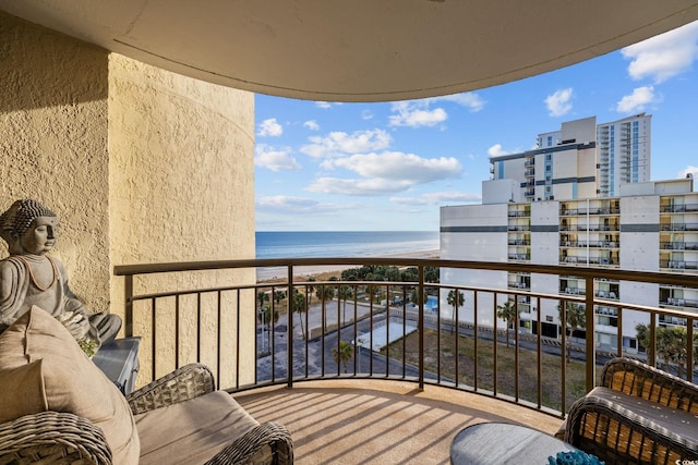 balcony with a water view and a view of the beach