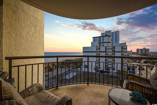 balcony at dusk featuring a water view