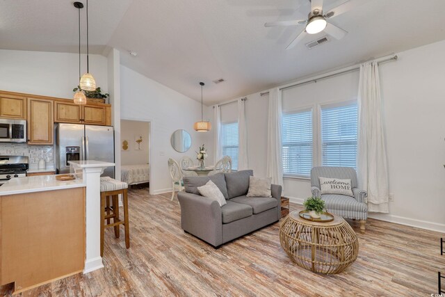 living room with ceiling fan, high vaulted ceiling, and light wood-type flooring