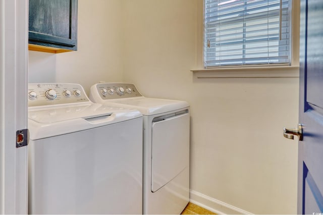 clothes washing area featuring separate washer and dryer and cabinets