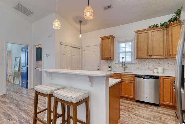 kitchen featuring pendant lighting, sink, stainless steel appliances, and light wood-type flooring