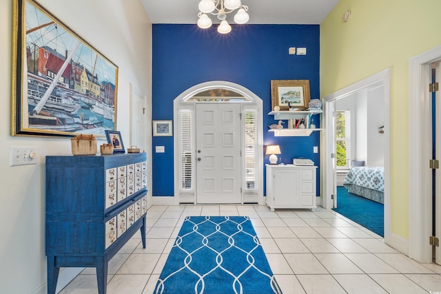 tiled entryway with a towering ceiling and a chandelier