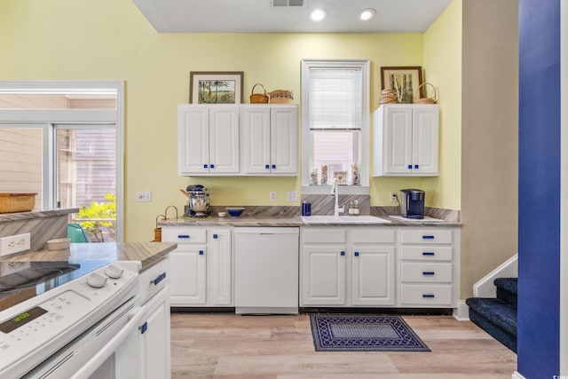 kitchen with white cabinetry, sink, white appliances, and light wood-type flooring