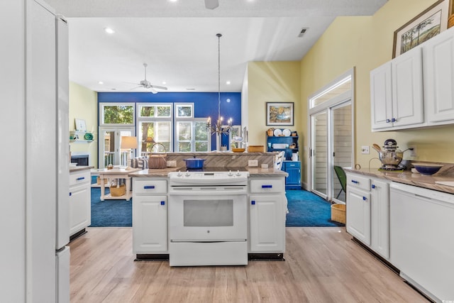 kitchen with white cabinetry, hanging light fixtures, white appliances, and ceiling fan with notable chandelier