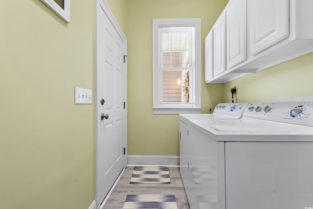 laundry area featuring cabinets, independent washer and dryer, and light hardwood / wood-style floors