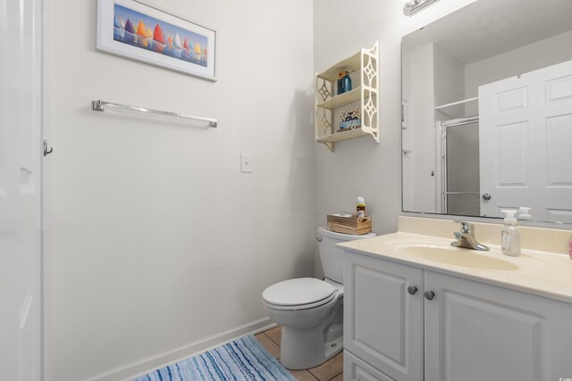 bathroom featuring vanity, tile patterned floors, toilet, and walk in shower