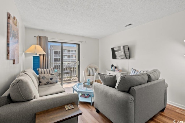 living room featuring a textured ceiling, wood finished floors, and visible vents