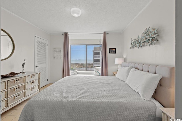 bedroom with a textured ceiling, ornamental molding, and light tile patterned flooring