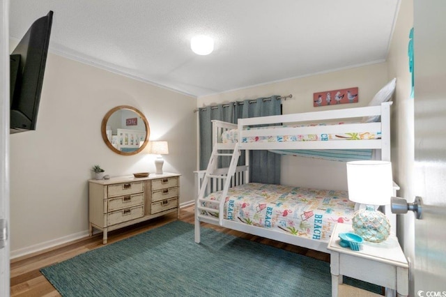 bedroom with baseboards, wood finished floors, and ornamental molding