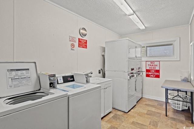 laundry area featuring a textured ceiling, a sink, washer and dryer, cabinet space, and stacked washer and clothes dryer