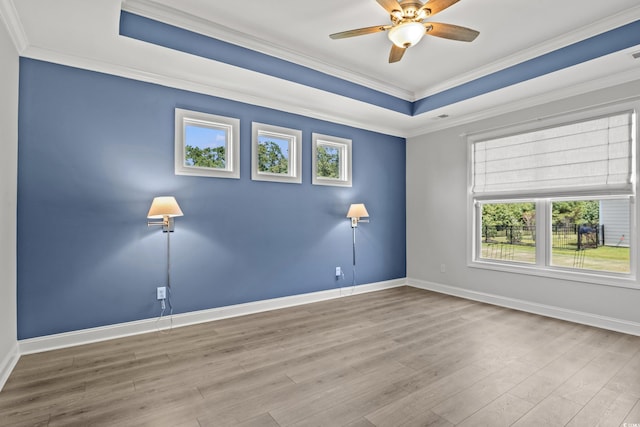 spare room with ceiling fan, ornamental molding, a tray ceiling, and light hardwood / wood-style floors