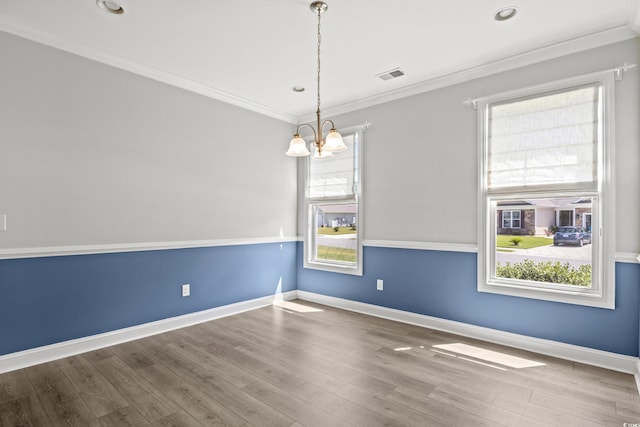 empty room with wood finished floors, baseboards, visible vents, ornamental molding, and a chandelier