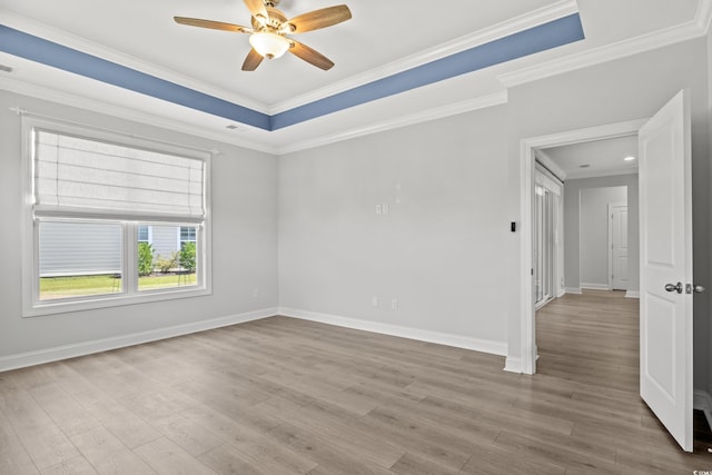 spare room with a raised ceiling, ornamental molding, ceiling fan, and light hardwood / wood-style floors