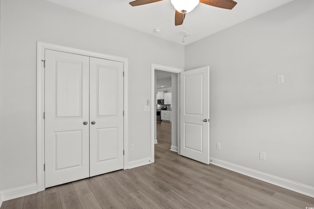 unfurnished bedroom featuring ceiling fan, light hardwood / wood-style floors, and a closet