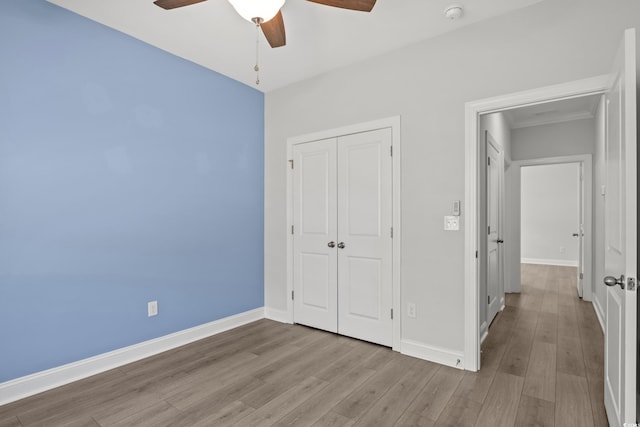 unfurnished bedroom featuring a ceiling fan, wood finished floors, baseboards, and a closet