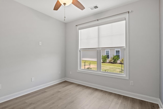 empty room featuring visible vents, a ceiling fan, light wood-type flooring, and baseboards