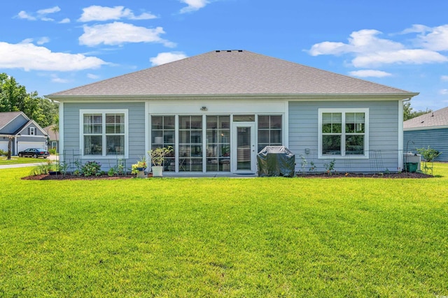 rear view of property featuring a lawn, roof with shingles, and a sunroom