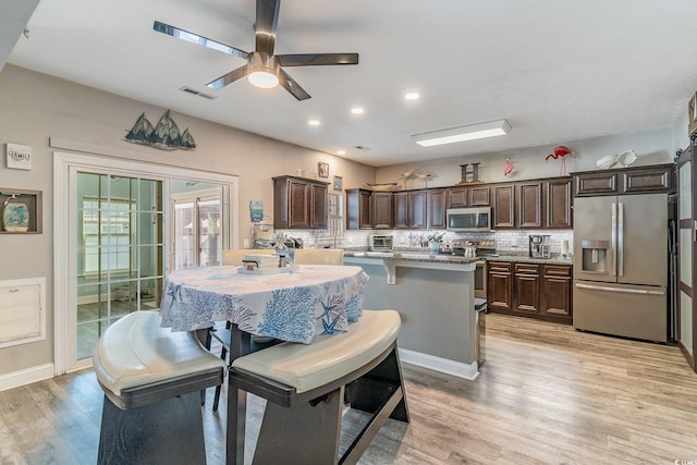 kitchen featuring a kitchen island with sink, a breakfast bar area, stainless steel appliances, and dark brown cabinetry