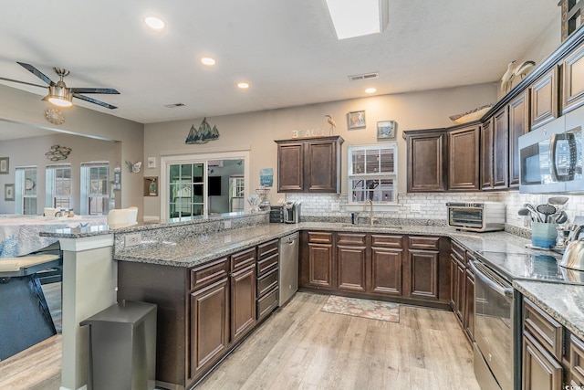 kitchen featuring stone counters, appliances with stainless steel finishes, sink, and kitchen peninsula