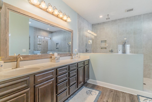 bathroom with a tile shower, vanity, and hardwood / wood-style flooring