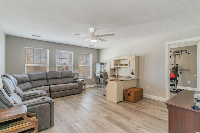 living room featuring a textured ceiling, ceiling fan, and light hardwood / wood-style flooring