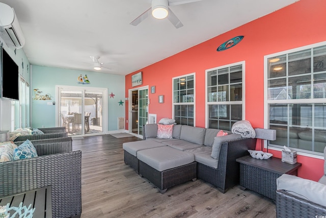 living room with hardwood / wood-style floors, a wall mounted air conditioner, and ceiling fan