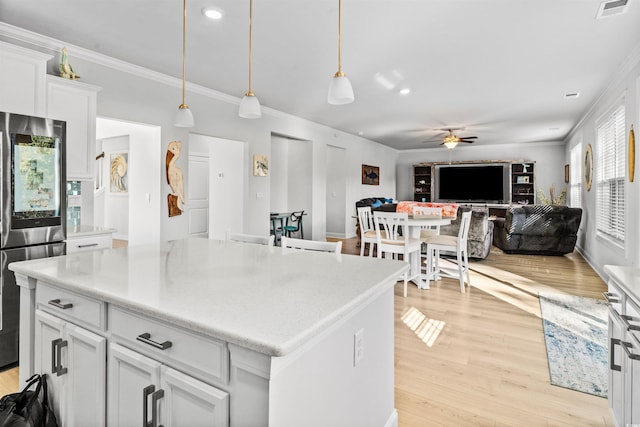 kitchen featuring white cabinetry, stainless steel refrigerator, a kitchen island, pendant lighting, and light hardwood / wood-style floors