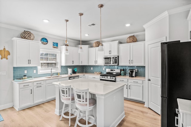 kitchen with sink, decorative light fixtures, a center island, appliances with stainless steel finishes, and white cabinets