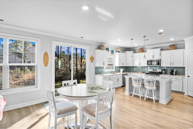 dining area with crown molding, sink, and light wood-type flooring