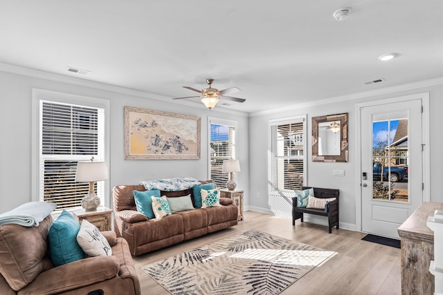 living room featuring ornamental molding, light hardwood / wood-style floors, and ceiling fan