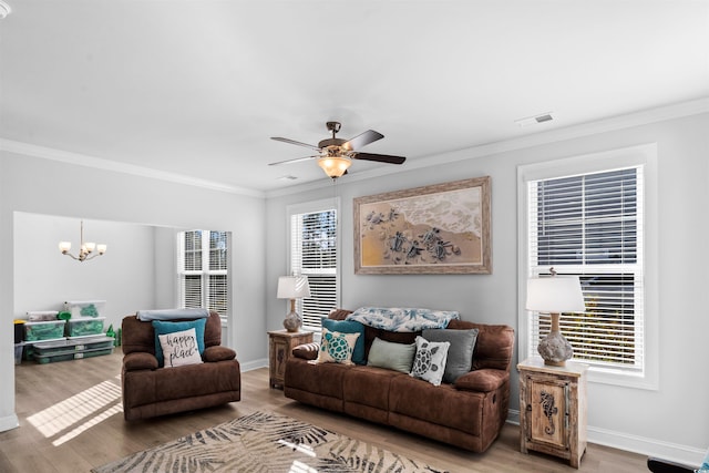 living room with hardwood / wood-style flooring, ornamental molding, and ceiling fan with notable chandelier