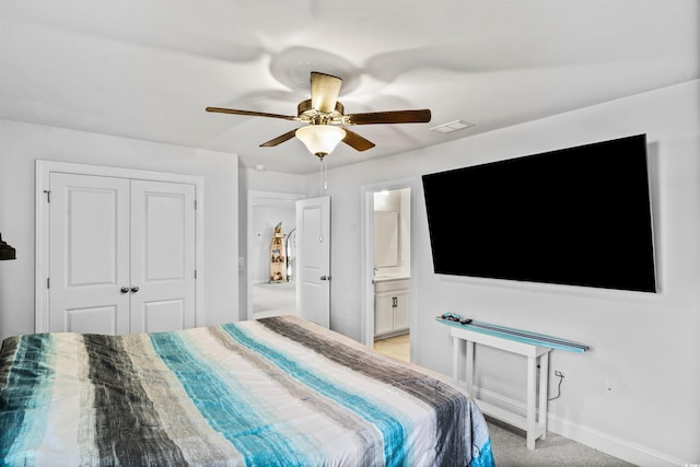 bedroom featuring ensuite bath, light colored carpet, ceiling fan, and a closet