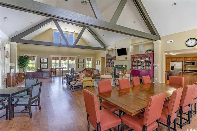 dining area with beamed ceiling, hardwood / wood-style floors, and high vaulted ceiling