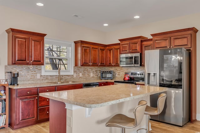 kitchen with appliances with stainless steel finishes, a center island, a breakfast bar area, and sink