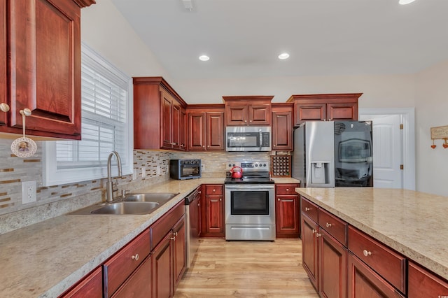 kitchen featuring stainless steel appliances, sink, light hardwood / wood-style floors, and decorative backsplash